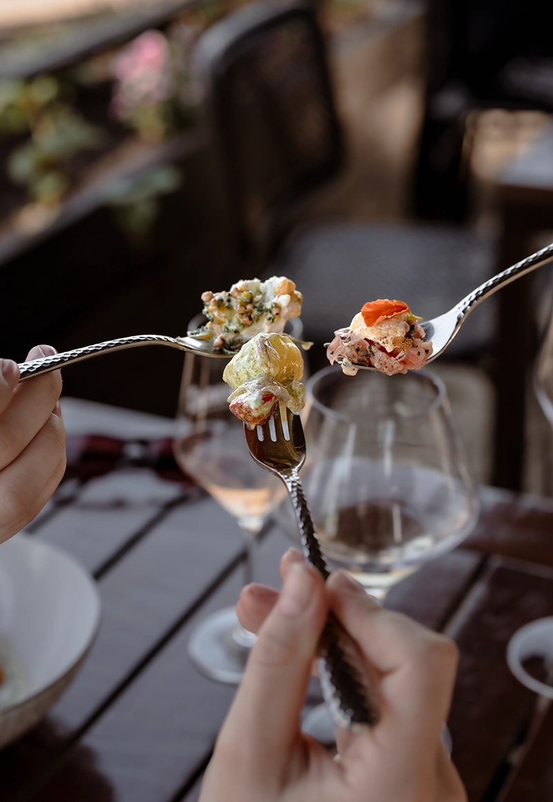 Drie vorken met heerlijke gerechten van Umai Resto Bar, op het terras.